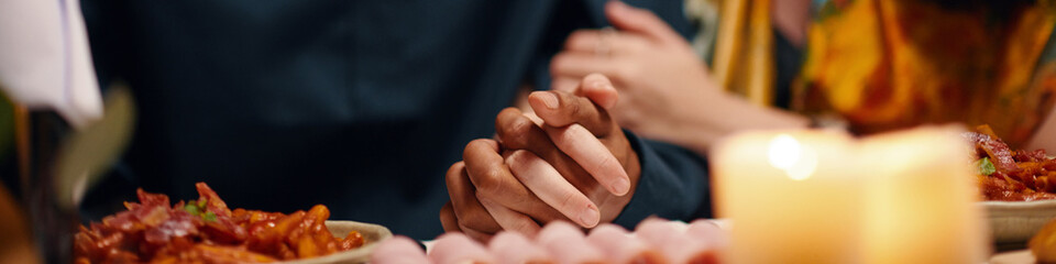 Long exposure of hands of affectionate sweethearts having festive dinner while sitting by served...