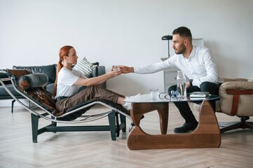 Side view. Woman is sitting in chair at an appointment with a psychologist