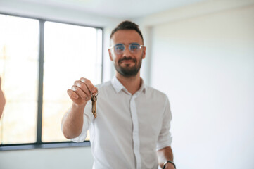 Fototapeta premium Realtor is standing and holding keys for new apartment