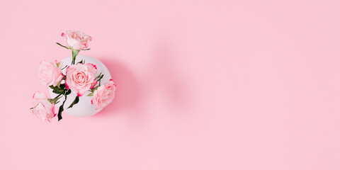 Pink roses in vase on pink background. Top view, flat lay. Banner