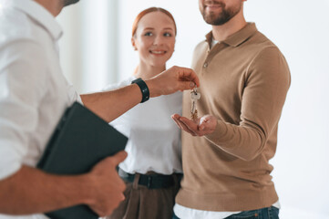 Customers bought the place, receiving the keys. Realtor shows an apartment to a young couple