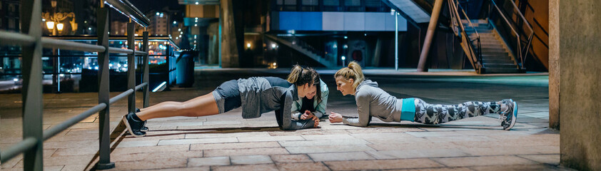 Young women friends sport team having fun while doing plank exercise during training together on...