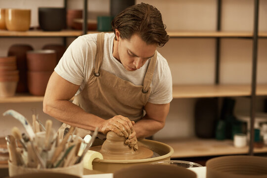 Ceramist shaping clay spinning on a wheel in a ceramic studio
