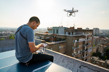 Man operating a drone with remote control on rooftop