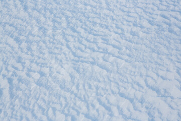 Beautiful winter background with snowy ground. Natural snow texture. Wind sculpted patterns on snow surface.