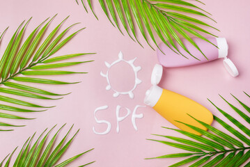 Mockup of Yellow and Pink cosmetic tube with sunscreen Cream in the form of sun SPF on pink background Copy Space Leaf Top View