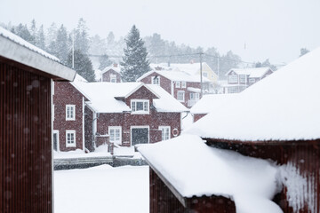 Fototapeta premium Scenic view of wooden cabins covered with snow at a lake in winter
