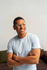 Smiling attractive young Latin man wearing casual clothes, stylish eyeglasses with crossed arms
