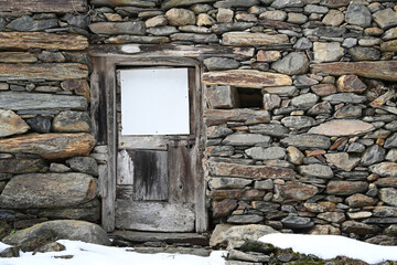 stone wall and door of a mountain house in winter