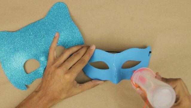 Hands use liquid silicone to glue blue diamond foam to mask, Catboy mask for carnival