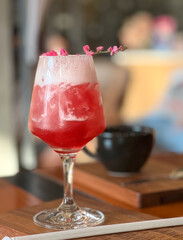 focus on a strawberry and rose flower smoothie mocktail served on wooden tray with blurred background
