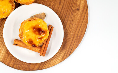 Pastel de nata tarts or Portuguese egg tart and cinnamon sticks isolated on white background. Pastel de Belem is a small pie with a crispy puff pastry crust and a custard cream filling.