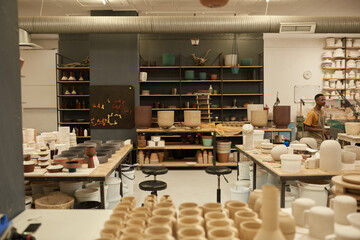 Young African ceramist at work in a large pottery studio - Powered by Adobe