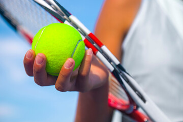 close-up of the hands of a female tennis player holding a tennis racket and a tennis ball	
