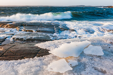 Crashing Waves Against Icy Shores Under Clear Skies at Sunset