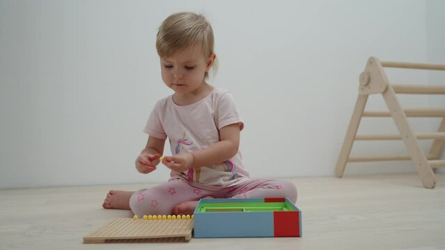 A small child 2.5 years old plays with a colored mosaic, laying it out on a substrate. Development of preschool children. Montessori toy games, educational toys for kids. Fine motor skills.