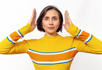Confident serious calm woman wearing yellow sweater isolated over white background. Hands near head.