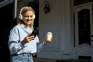 Fototapeta premium A girl in headphones and with a phone on the street.