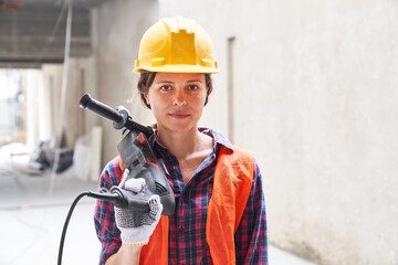 Portrait of confident young female construction worker wearing workwear carrying equipment at site