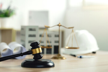 Labor, construction, and land law concepts. Judge gavel, scales of justice, protective helmet, building blueprint plans, and building model on wooden table. law of building construction, engineering. - obrazy, fototapety, plakaty