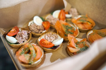 Cold snacks, sandwiches, ham and salmon are delivered in a cardboard box.