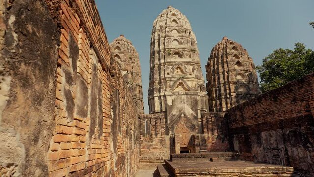 Wat Si Sawai at Sukhothai Historical Park. Three prangs (pagodas) are surrounded by a laterite wall. Inside the wall, the viharn in the west, built of laterite in the Lop Buri or Hindu-style