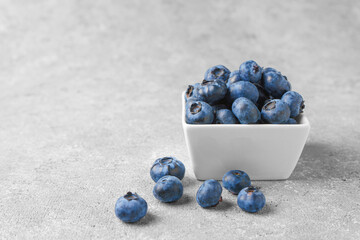Fresh blueberries in a small square bowl on gray concrete background with copy space. Organic berries, healthy food, wild berries