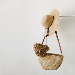 Women's fashion accessories. Stylish female straw handbag, straw hat and dried flower on hanger...