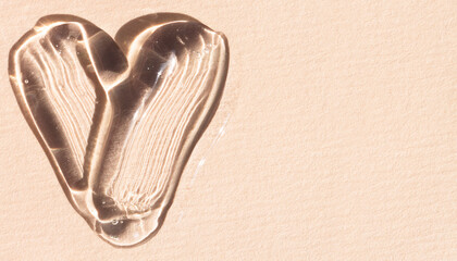 Transparent serum, gel in the shape of a heart on a beige background with copy space, banner flat...