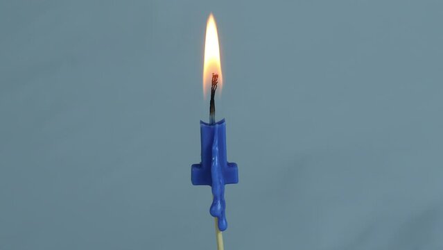 close up on timelapse melting a blue letter I birthday candle on a white background.
