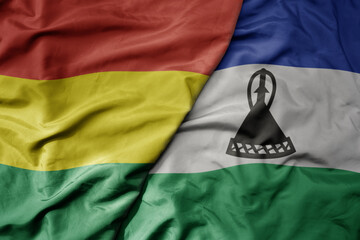big waving national colorful flag of lesotho and national flag of bolivia .