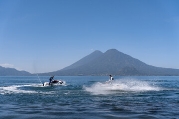 Fototapeta premium Two Young Hispanic Men Drifting Water with Jet-Skis in Atitlan Lake, Guatemala
