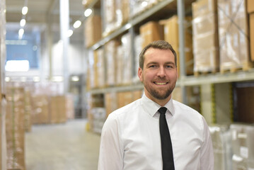 portrait friendly businessman/ manager in suit working in the warehouse of a company