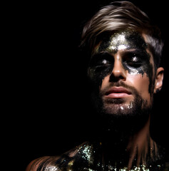 Fashion editorial Concept. Closeup portrait of handsome man chiseled features, striking shiny black glitter shimmer sparkle makeup. illuminated dynamic composition dramatic lighting. copy text space