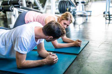 Fototapeta premium Sport active caucasian man and woman friend doing plank position indoor sport gym