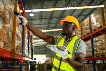 Picture of an African young man stock check and barcode scan in the warehouse. Holding a digital...