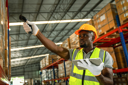 Picture of an African young man stock check and barcode scan in the warehouse. Holding a digital tablet in his hands.