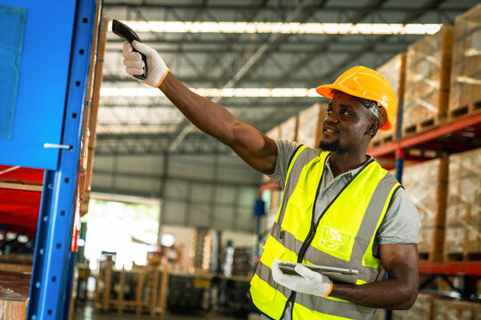 Picture of an African young man stock check and barcode scan in the warehouse. Holding a digital tablet in his hands.