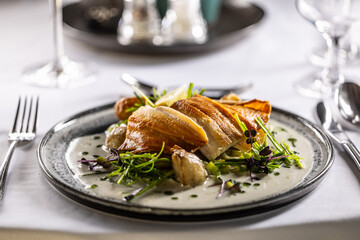 Lightly smoked trout fillet, baked potatoes, beurre blanc sauce, leek and lime dressing. Creatively served fish on a plate in restaurant