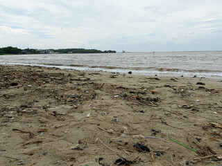 Dirty beach with waste and murky sea water