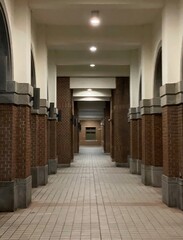 At a serene night, the corridor of the library is lined with round-arched red brick pillars, illuminated by lights.
