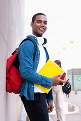 Portrait of a happy young African American man with a notebook looks at the camera and smiles.