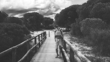 a woman standing on a wooden bridge in a forest