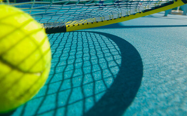 tennis racket and ball on a tennis court on a bright sunny day