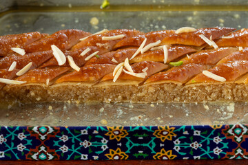 A piece of traditional Iranian baklava in the ornate metal box in which it is sold. 