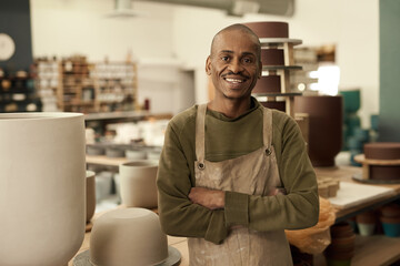 African potter smiling while standing in a pottery workshop - Powered by Adobe