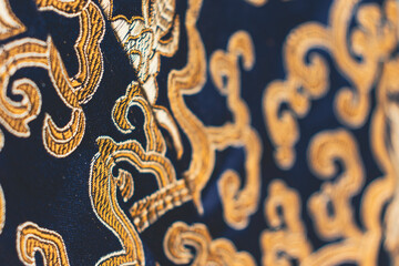 Close up of a deep blue and gold brocade fabric. Copy space
