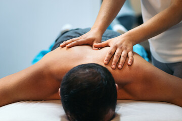 young woman treating a male patient. back massage physiotherapy. close-up. front view