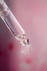 A drop of cosmetic aromatic oil drips from the pipette. Front view.