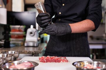 Chef cuts pork ribs, salts them and peppers them in the restaurant kitchen.